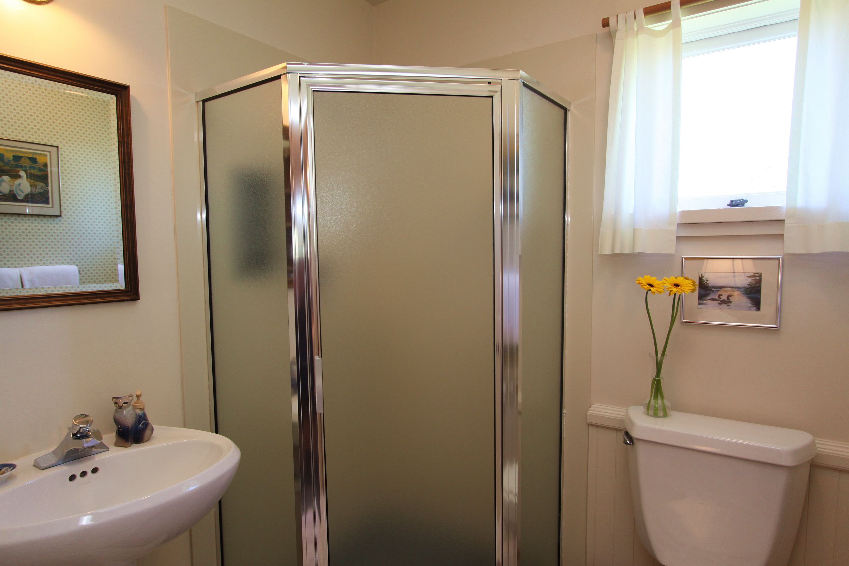 A bathroom with a glass-enclosed shower, a white sink, and a toilet.