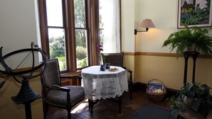 A cozy room with a round table, two chairs, a lamp, and a potted plant. - Joshua Grindle Inn (Mendocino)