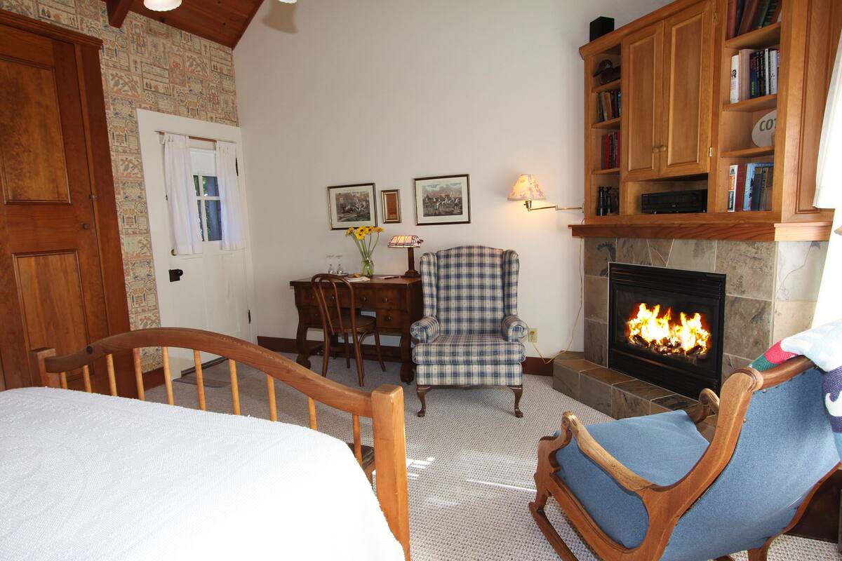 A cozy living room with a fireplace, wooden furniture, and a checkered armchair.