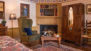 A traditional living room with a fireplace, a bookshelf, and a green armchair. - Asa Ransom House (Clarence)