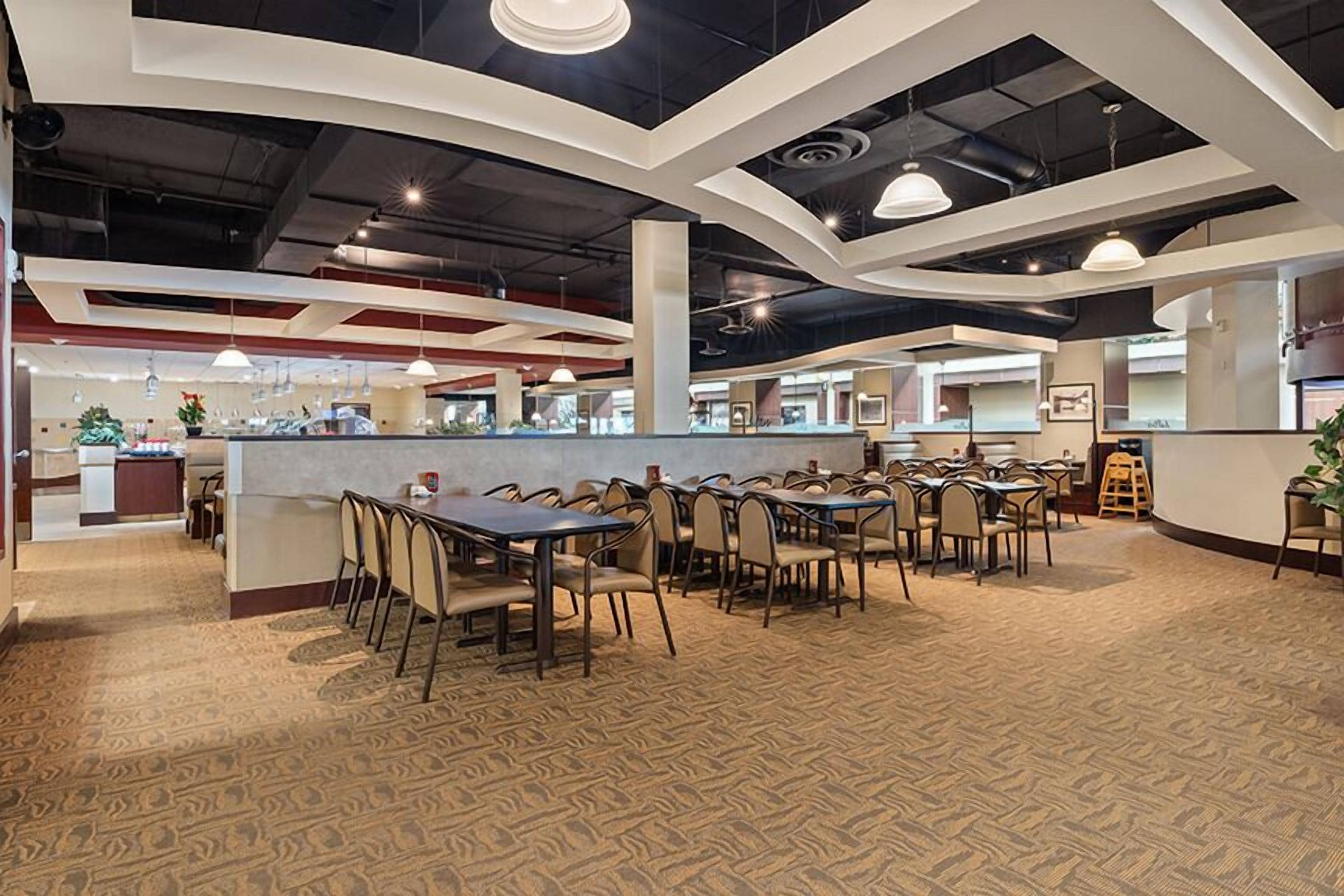 A spacious indoor area with multiple tables and chairs, a central counter, and a patterned carpet.