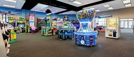 A gaming arcade with various machines, carpeted floor, and ceiling lights.