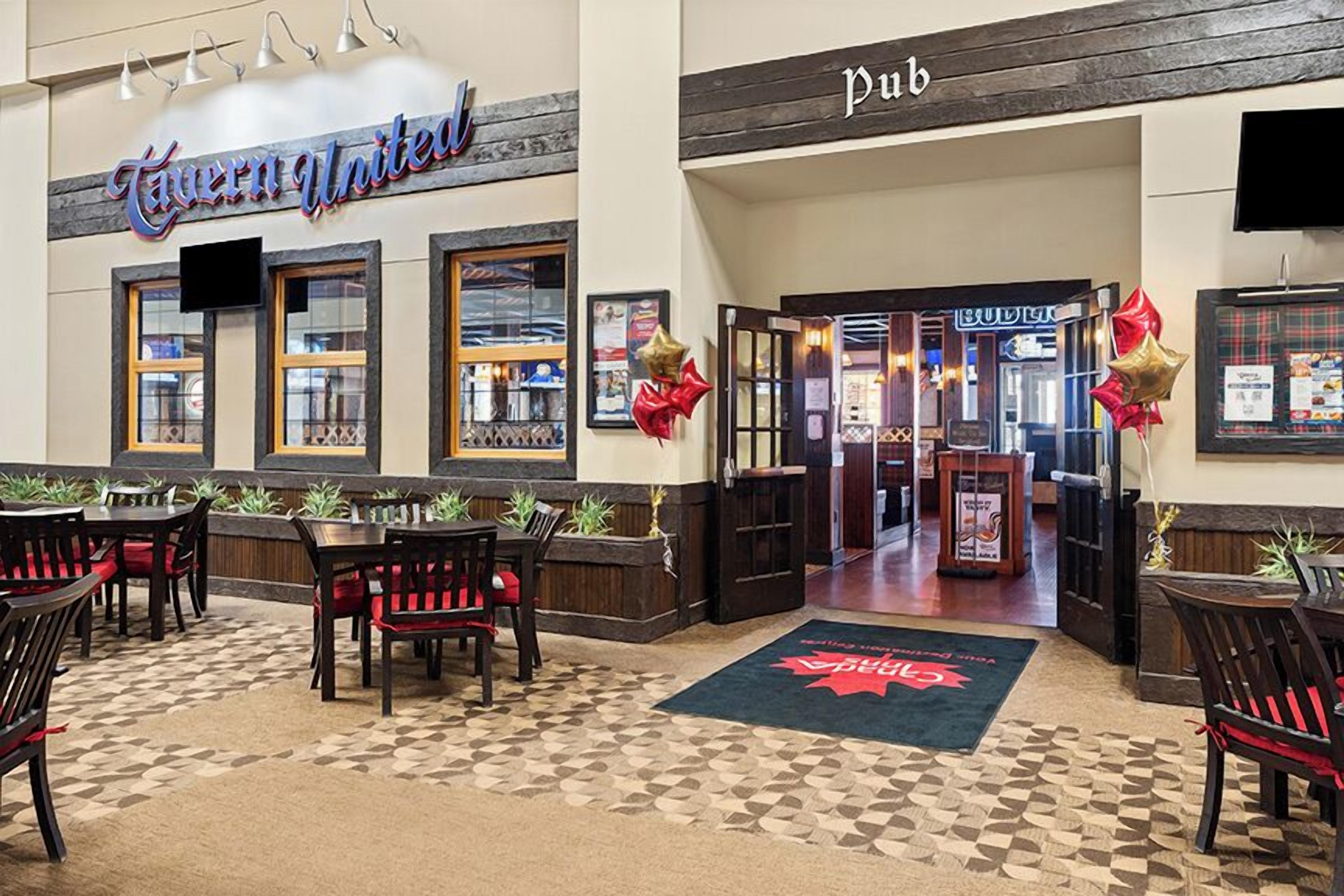 Un pub con suelo de cuadros, mobiliario de madera y un cartel que dice 'Queen United'.