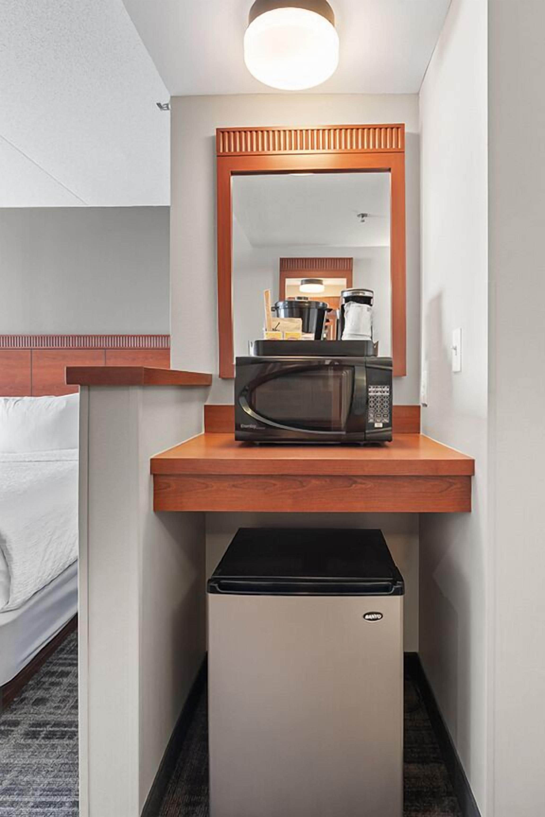 A compact kitchenette with a microwave, a small refrigerator, and a wooden countertop.
