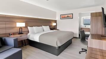 Una habitación de hotel moderna con una cama grande, mesitas de noche, un escritorio y una silla.