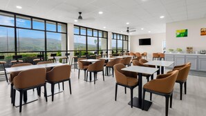A spacious dining area with tables and chairs, large windows offering a view of the landscape, and a ceiling fan. - Quality Inn Wytheville (Wytheville)