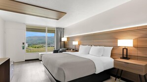A modern hotel room with a large bed, bedside lamps, a nightstand, and a view of the outdoors. - Quality Inn Wytheville (Wytheville)