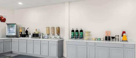 A modern kitchen area with a refrigerator, microwave, and various appliances on a white countertop.