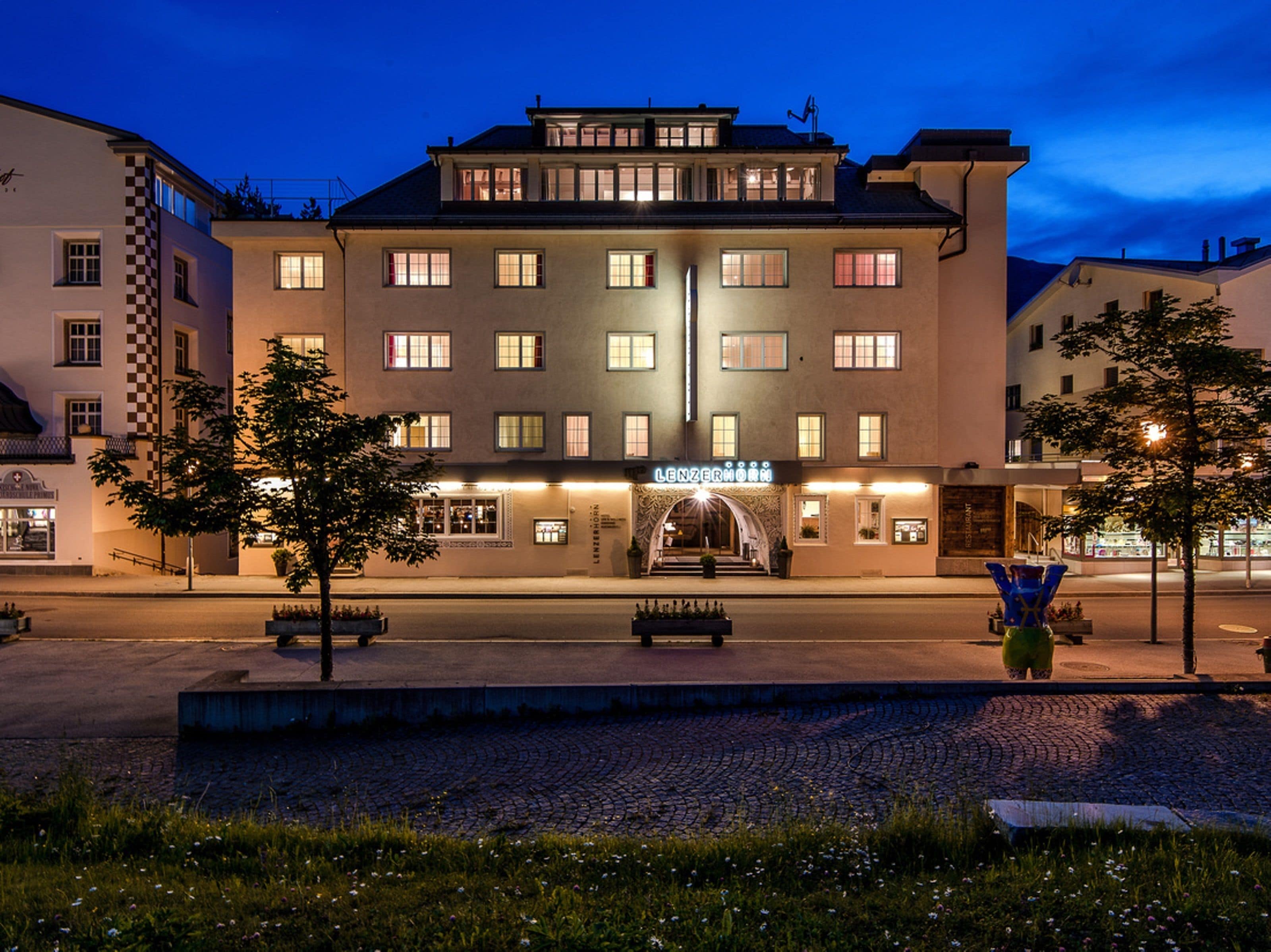 Un hotel con entrada central, múltiples ventanas y fachada bien iluminada.