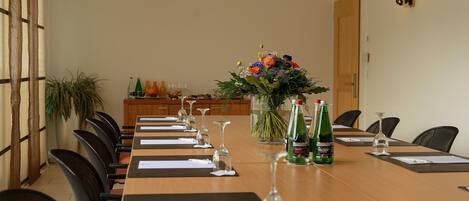 A conference room with a long table, chairs, and a floral centerpiece.