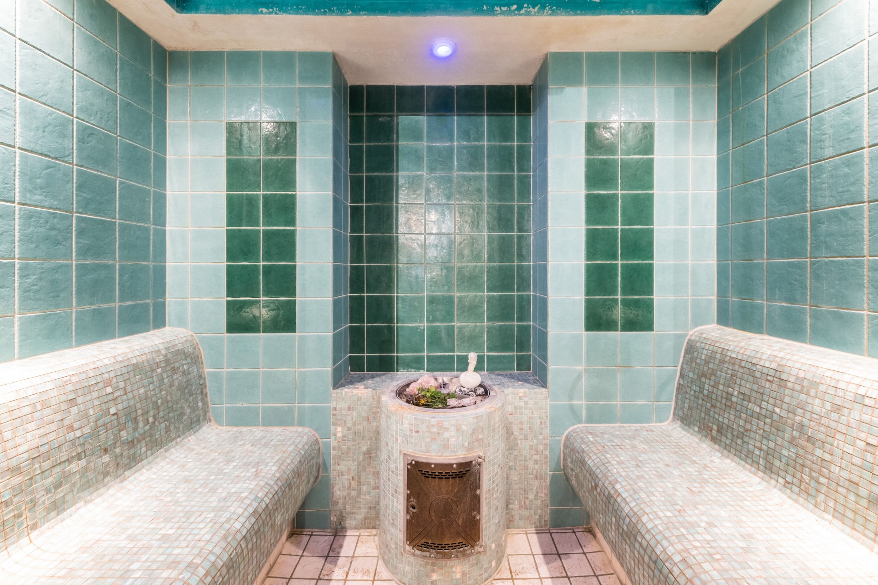 Ein Badezimmer mit zwei Sitzbereichen, einer Fliesenwand und einem Mittelwaschbecken mit einem dekorativen Gegenstand.