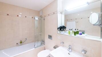 Une salle de bain moderne avec une douche à parois de verre, des toilettes blanches et un lavabo avec un miroir au-dessus.