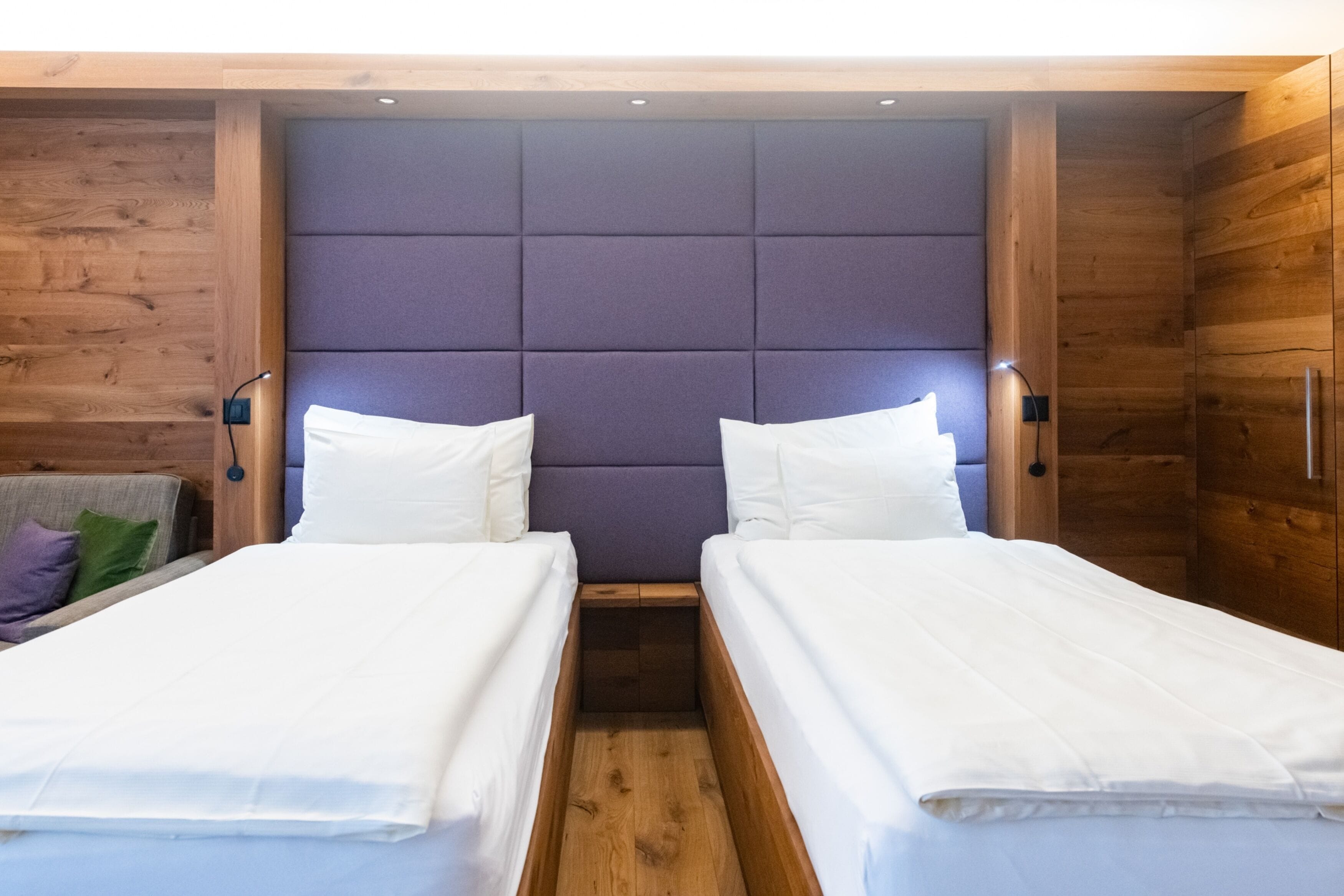 Een tweepersoonsbed met hoofdeinde, twee nachtkastjes en een houten wand.
