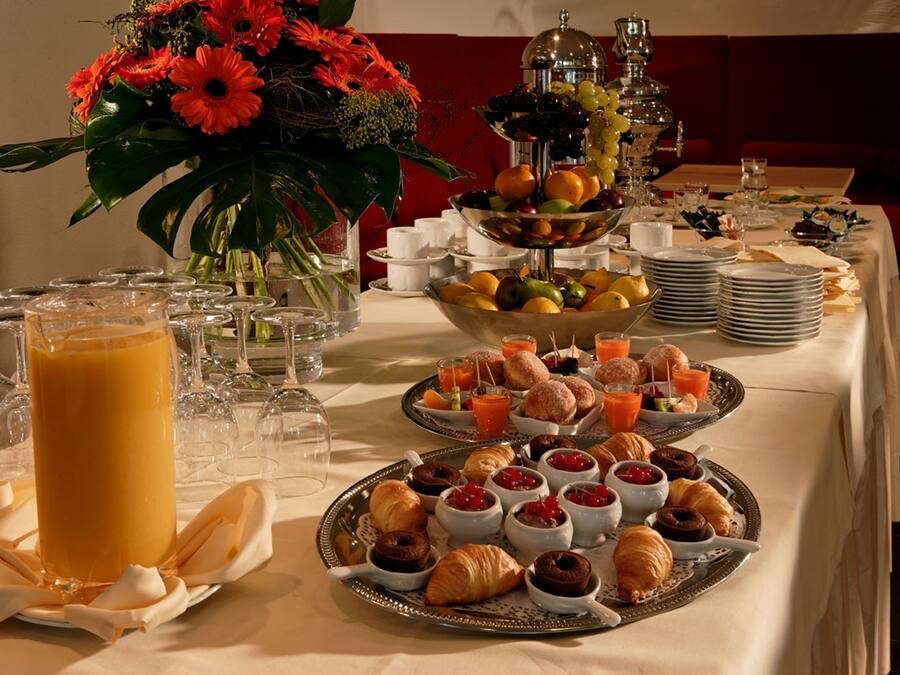A breakfast buffet with various pastries, fruits, and juices.