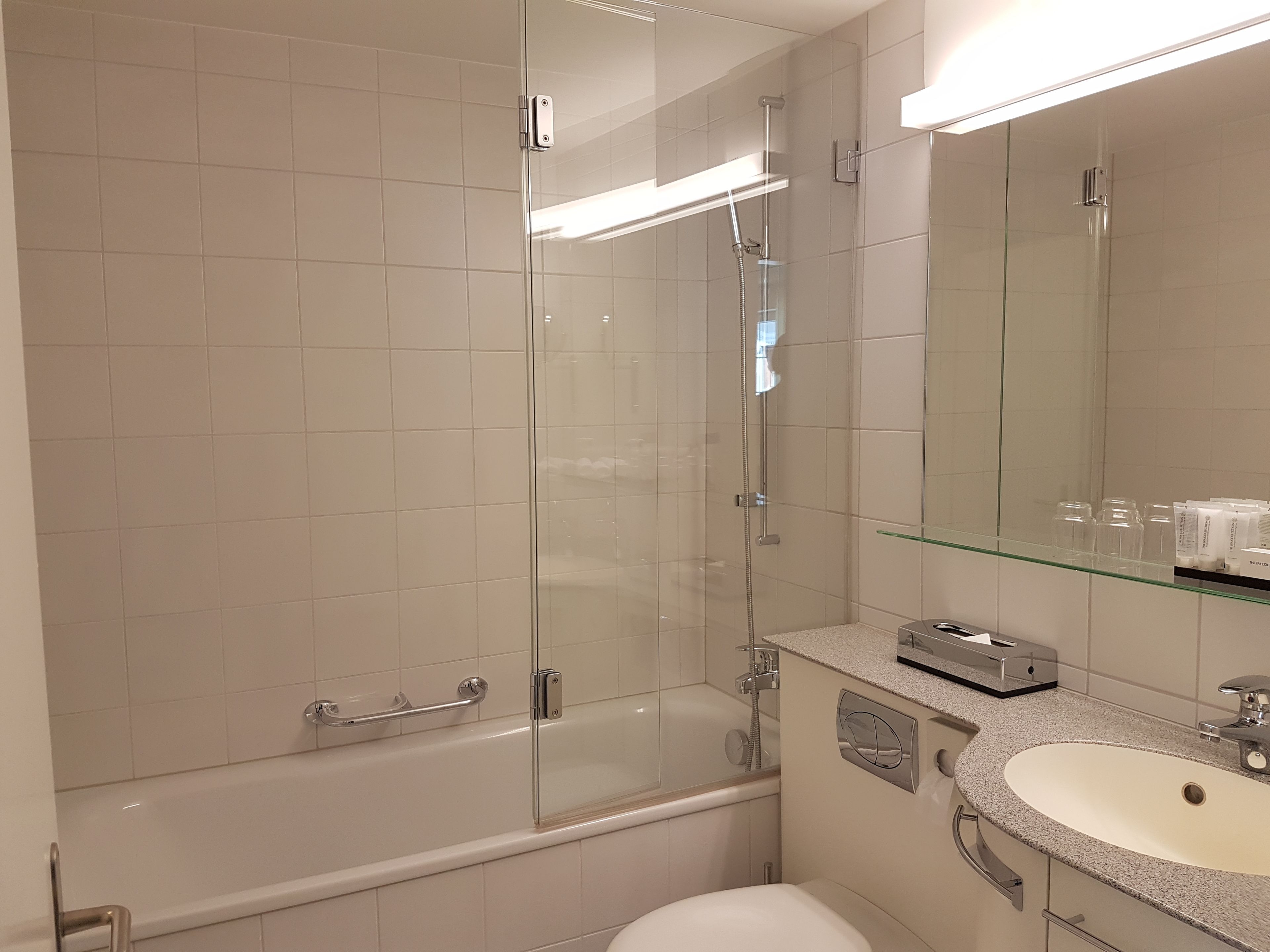Un baño moderno con ducha de vidrio, una bañera, un lavabo con encimera y un espejo.
