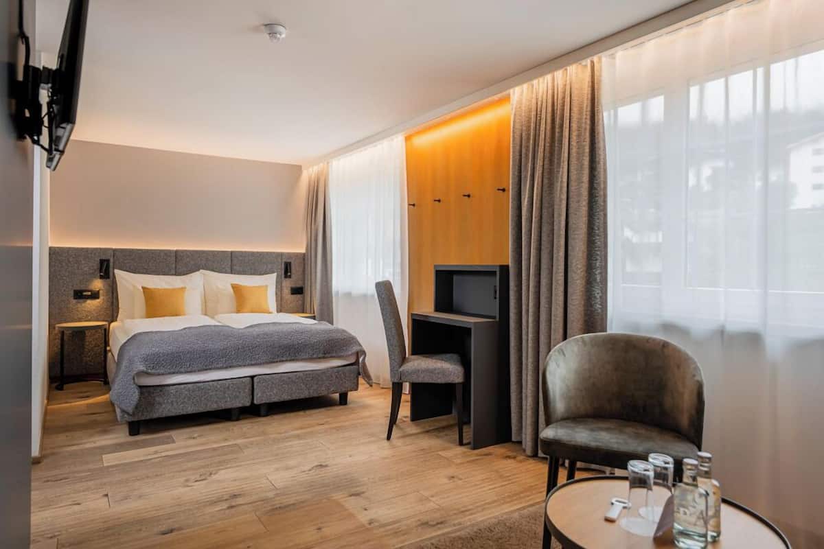 Una habitación de hotel moderna con una cama, un escritorio, una silla y un televisor.