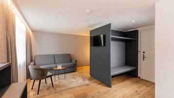 A modern room with a grey sofa, a small round table, and a TV mounted on a grey wall.