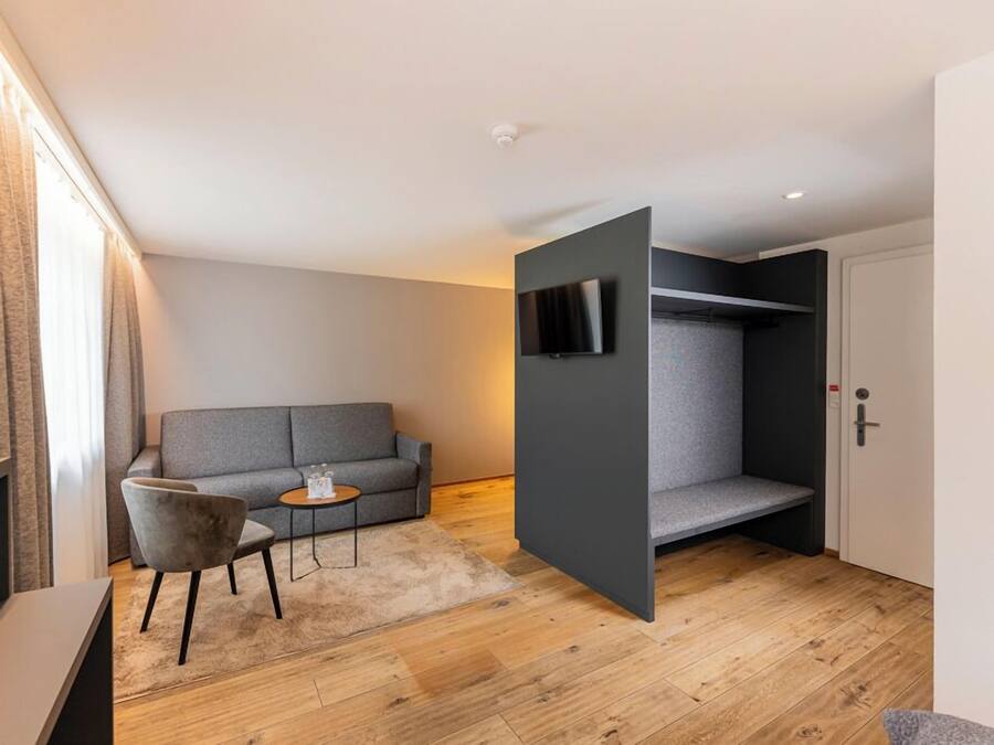 A modern room with a grey sofa, a small round table, and a TV mounted on a grey wall.