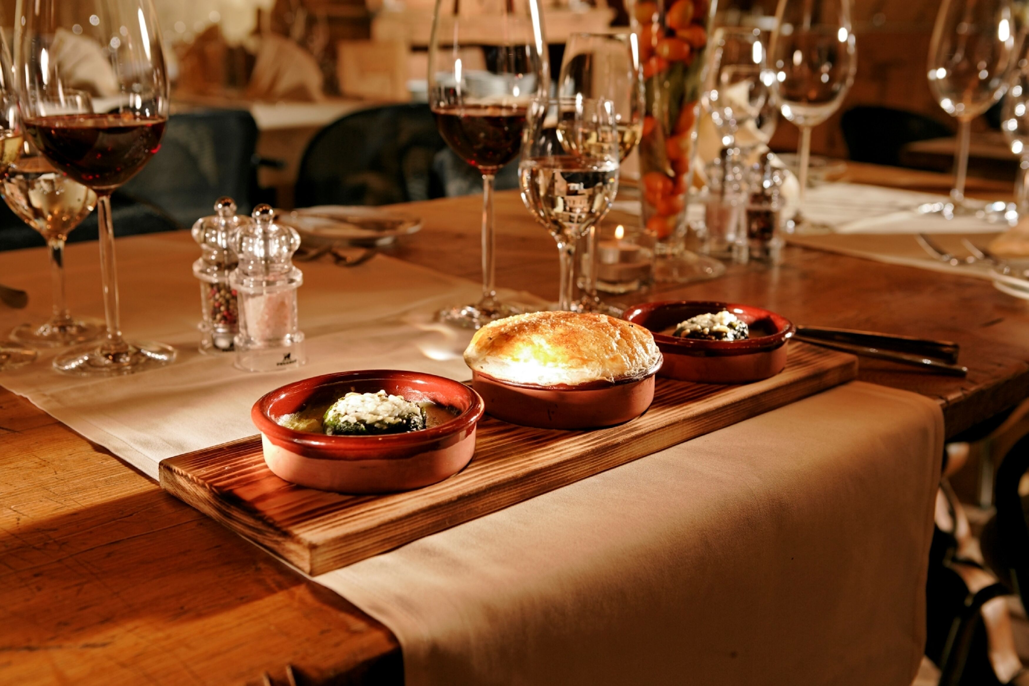 Una mesa de comedor con varias copas de vino, un panecillo y dos pequeños recipientes de comida.