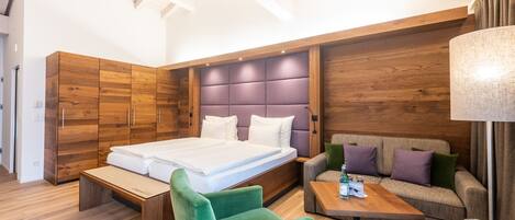 A modern bedroom with a large bed, wooden wardrobe, sofa, and a small table.