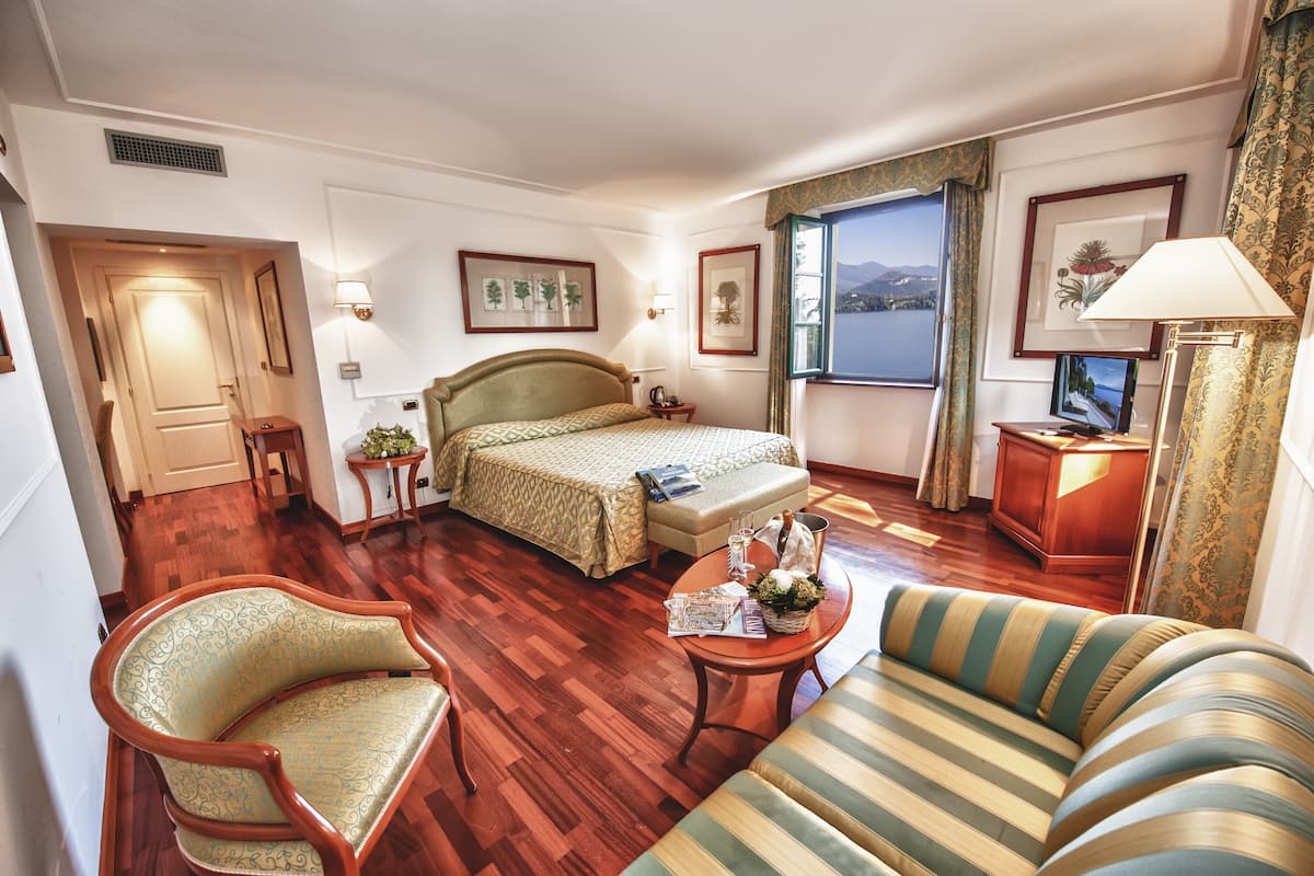 Hotelkamer met een bed, een bank, een stoel, een tafel met een lamp en een raam met uitzicht.