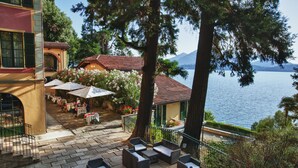 Una terraza con mesas al aire libre, vista a un lago y una montaña al fondo.