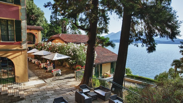 Una terraza con mesas al aire libre, vista a un lago y una montaña al fondo.
