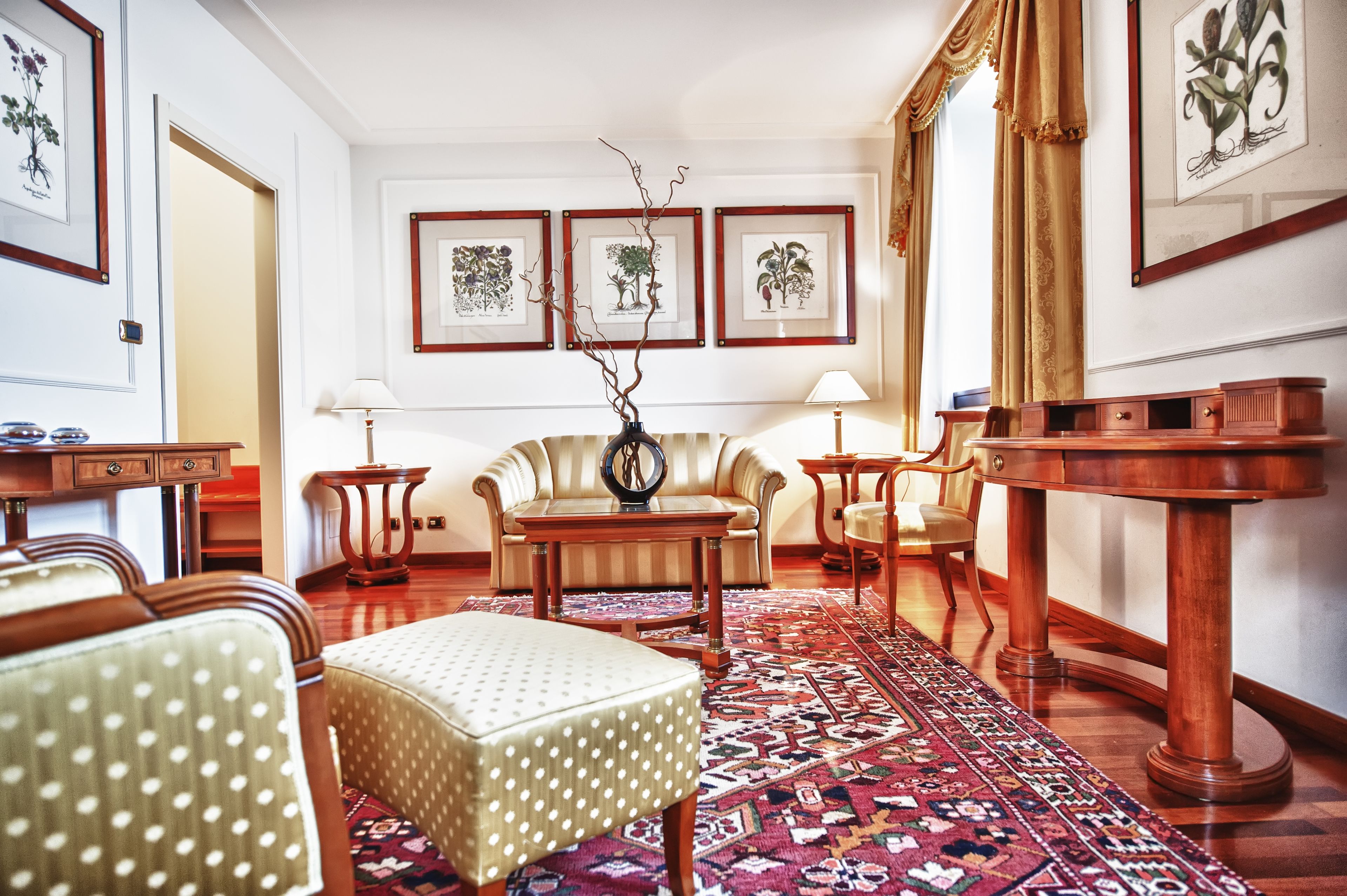 Une pièce comprenant un canapé, des fauteuils, une table basse, une table d’appoint et un tapis à motifs.