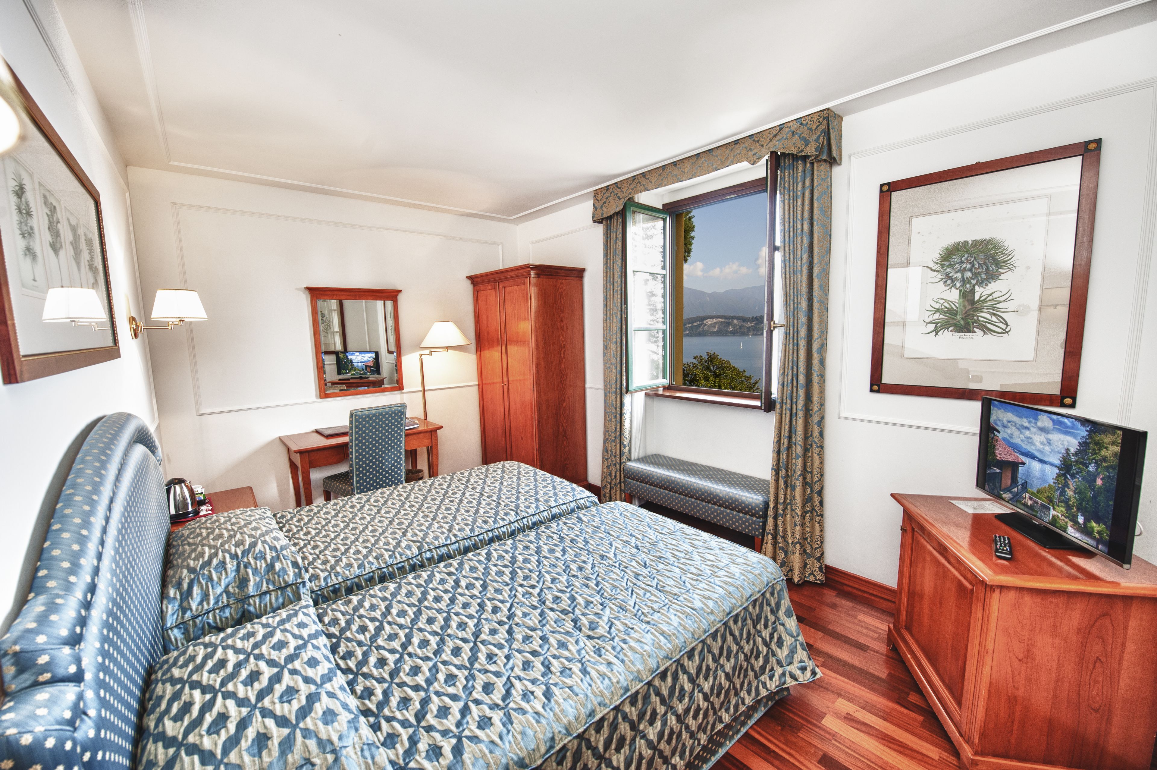 Une chambre d’hôtel avec un grand lit, un bureau avec une chaise, une télévision et une fenêtre donnant sur la mer.