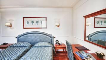 Une chambre d’hôtel comprenant un lit, un bureau, une chaise, une table de chevet et un miroir.