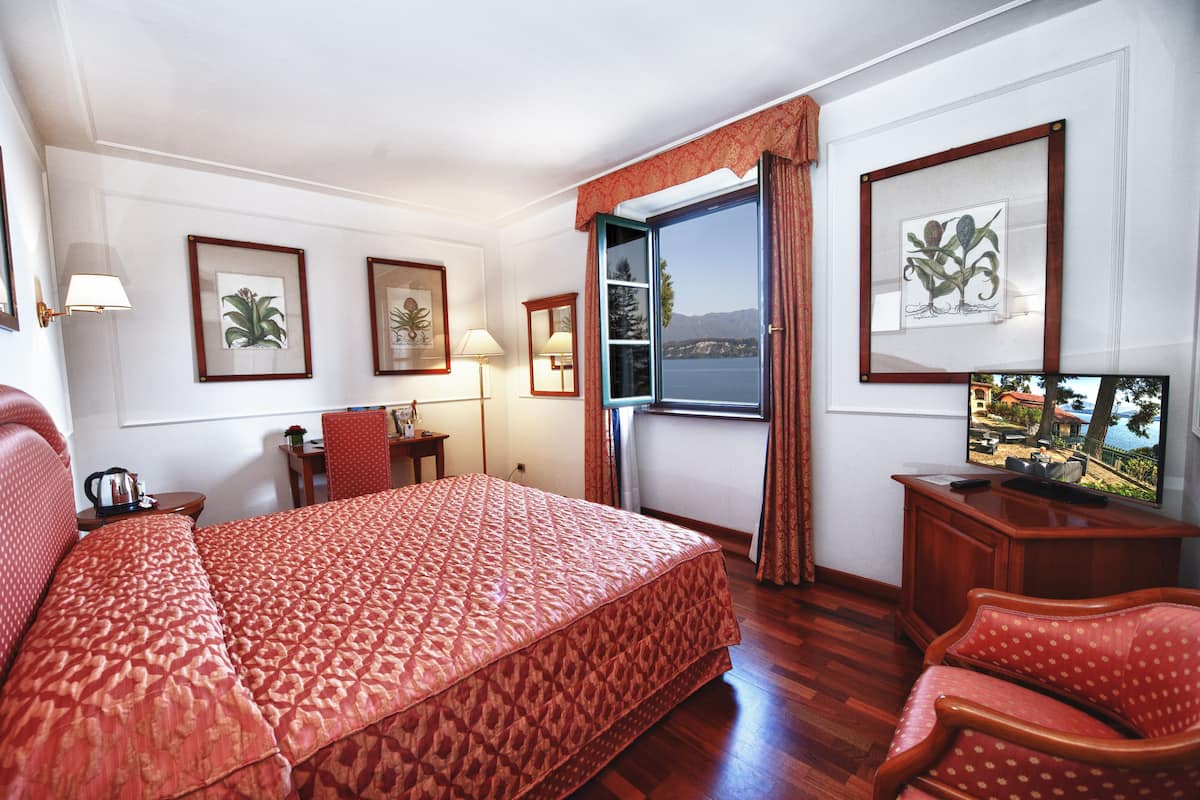Hotelkamer met een groot bed, een bureau, een stoel, een televisie en een raam met gordijnen.