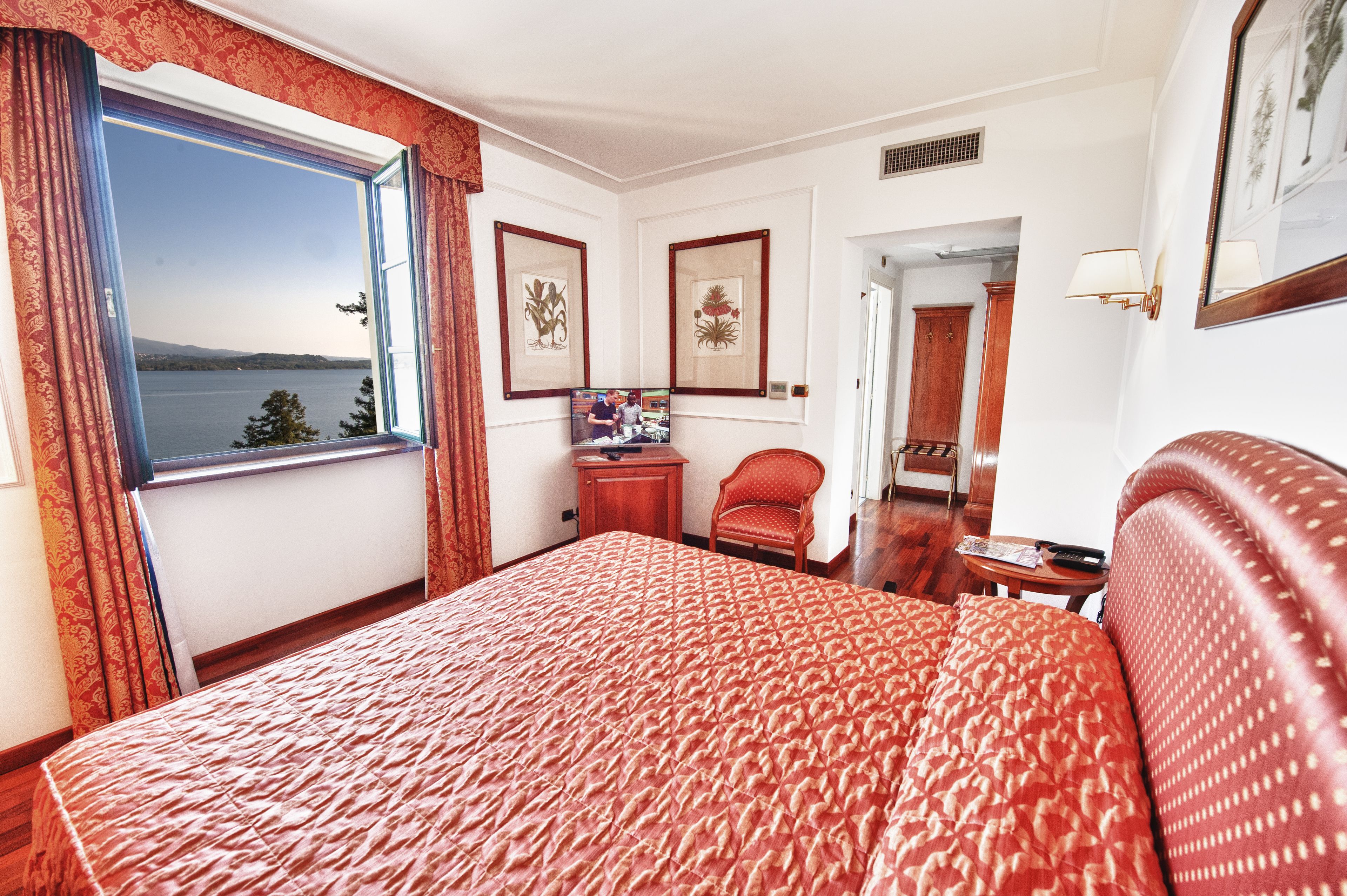 Una habitación de hotel con una cama grande, un escritorio, una silla, un televisor y una ventana con cortinas.