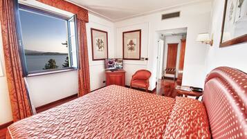 Una habitación de hotel con una cama grande, un escritorio, una silla, un televisor y una ventana con cortinas.