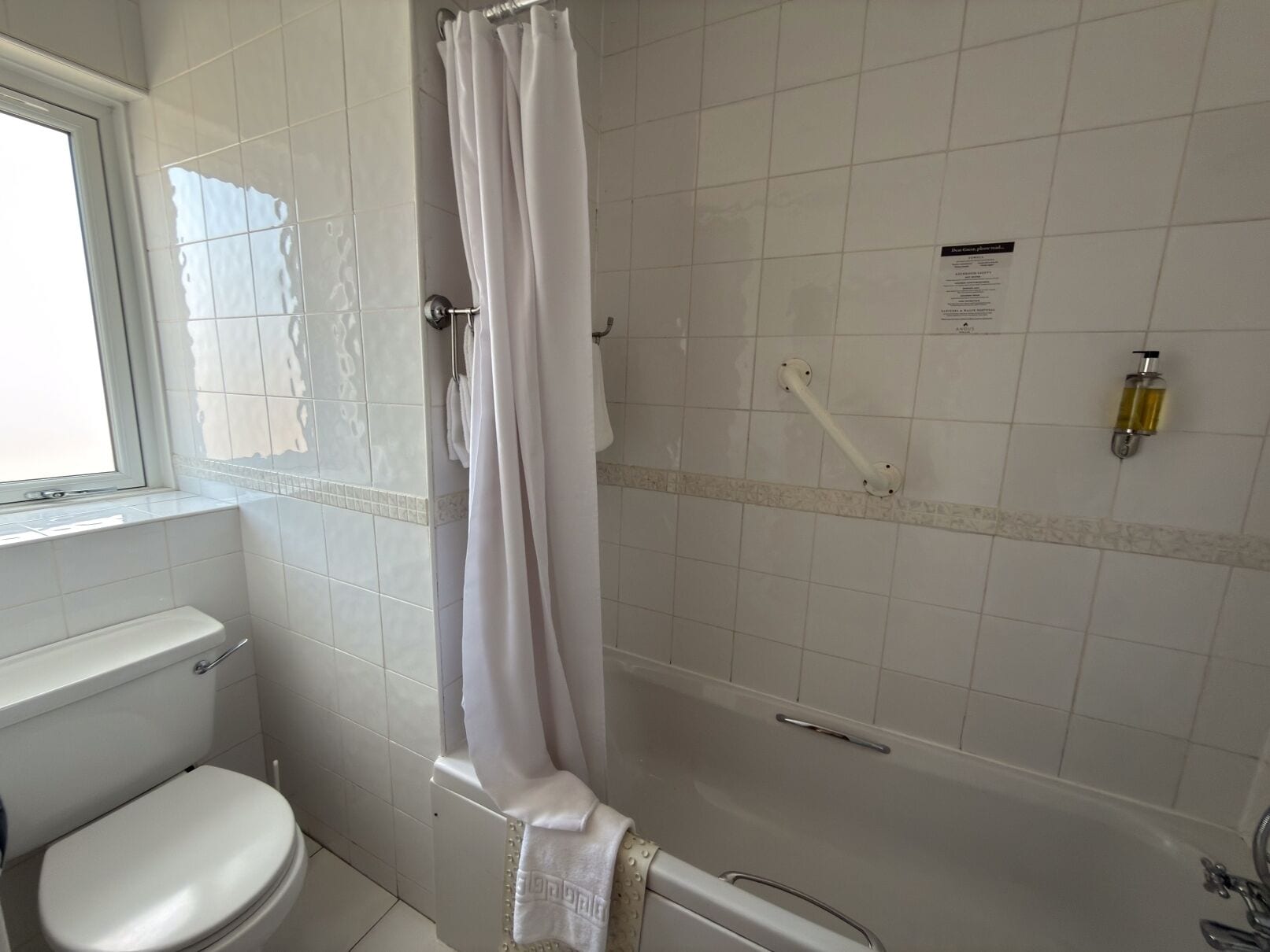 A bathroom with a toilet, a shower with a curtain, and a bathtub.