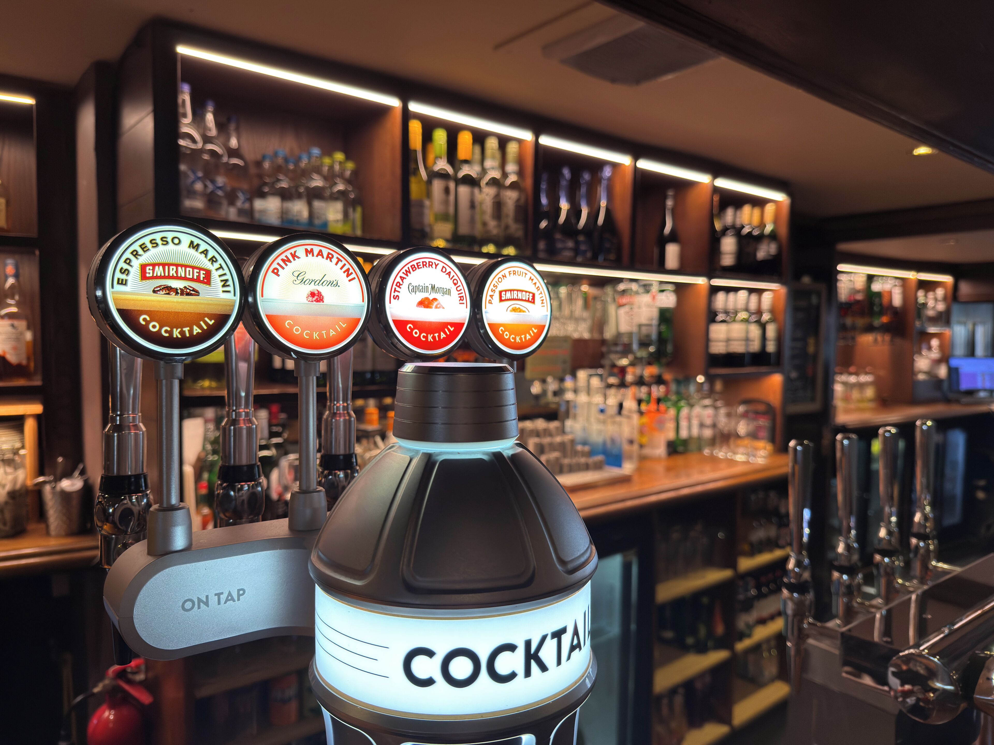A bar area with multiple cocktail taps and a prominently displayed bottle labeled 'COCKTAIL'.
