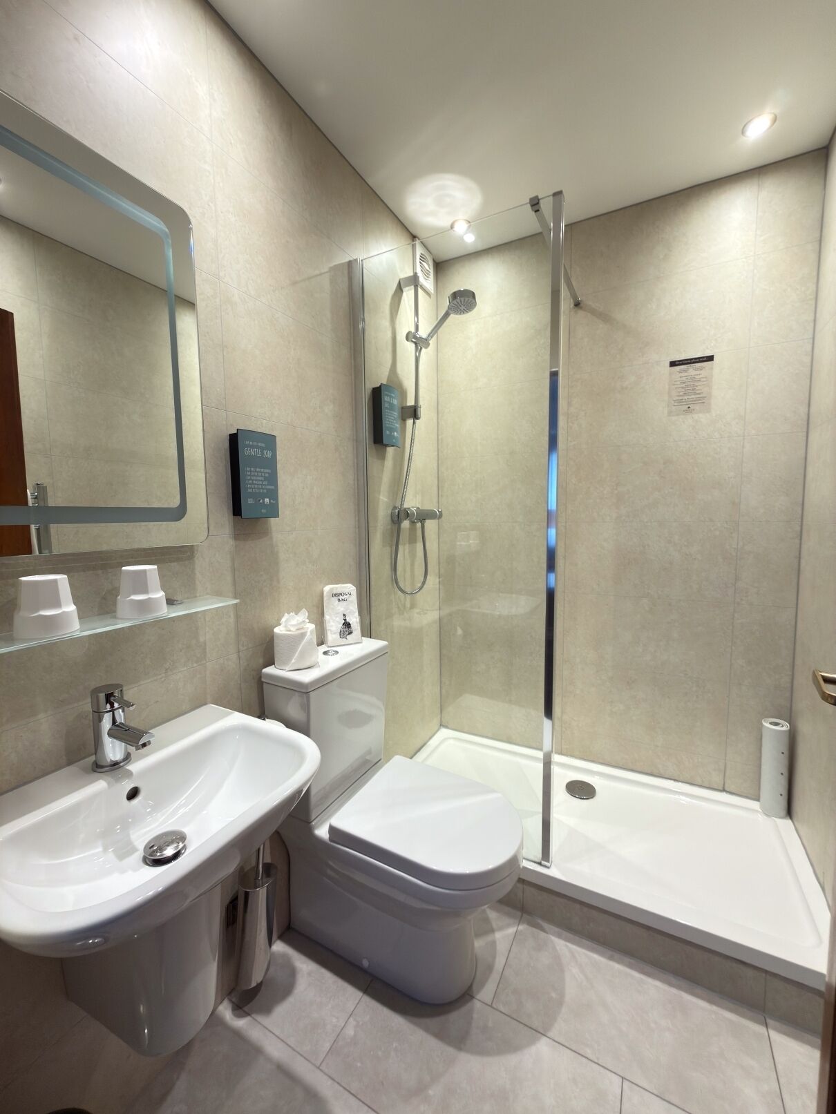 A modern bathroom with a glass-enclosed shower, a white sink, and a toilet.