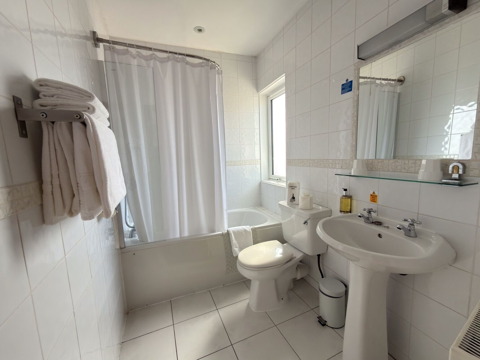 Un baño con bañera, inodoro y lavamanos, todo en blanco.