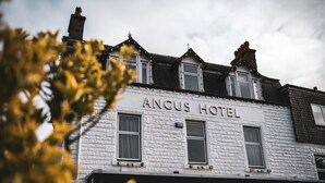 Het uiterlijk van Hotel Angus, met een klassieke architectuur, een opvallend bord en meerdere ramen.