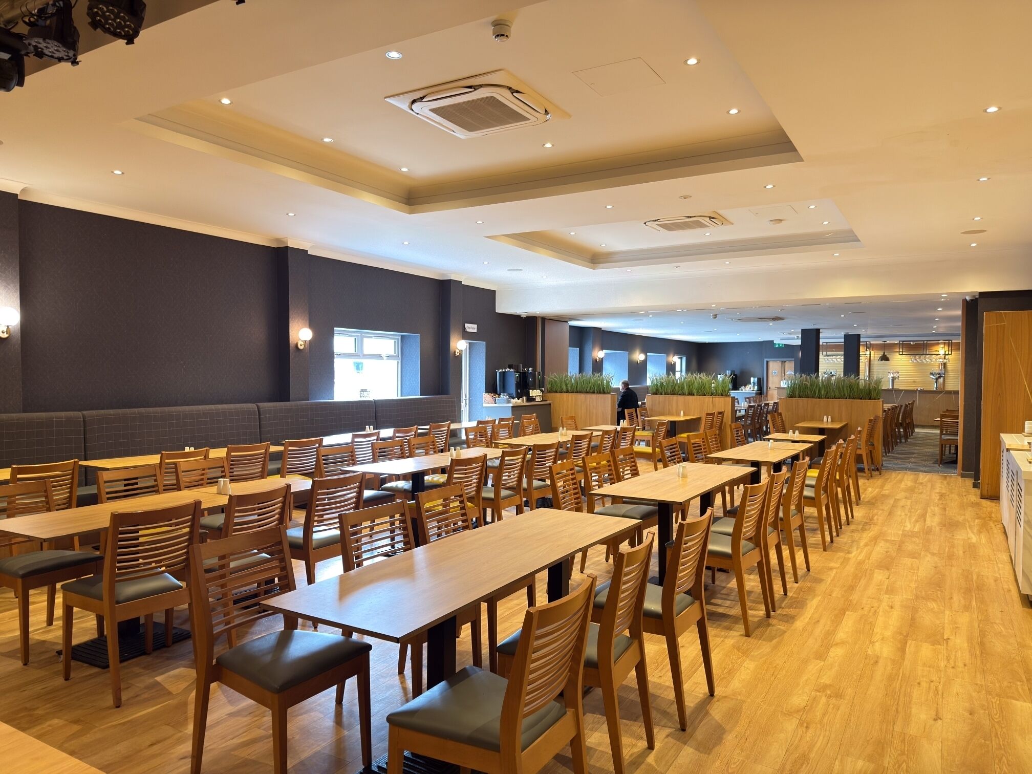 A spacious dining area with multiple tables and chairs, a counter with a menu, and a seating area with a sofa.