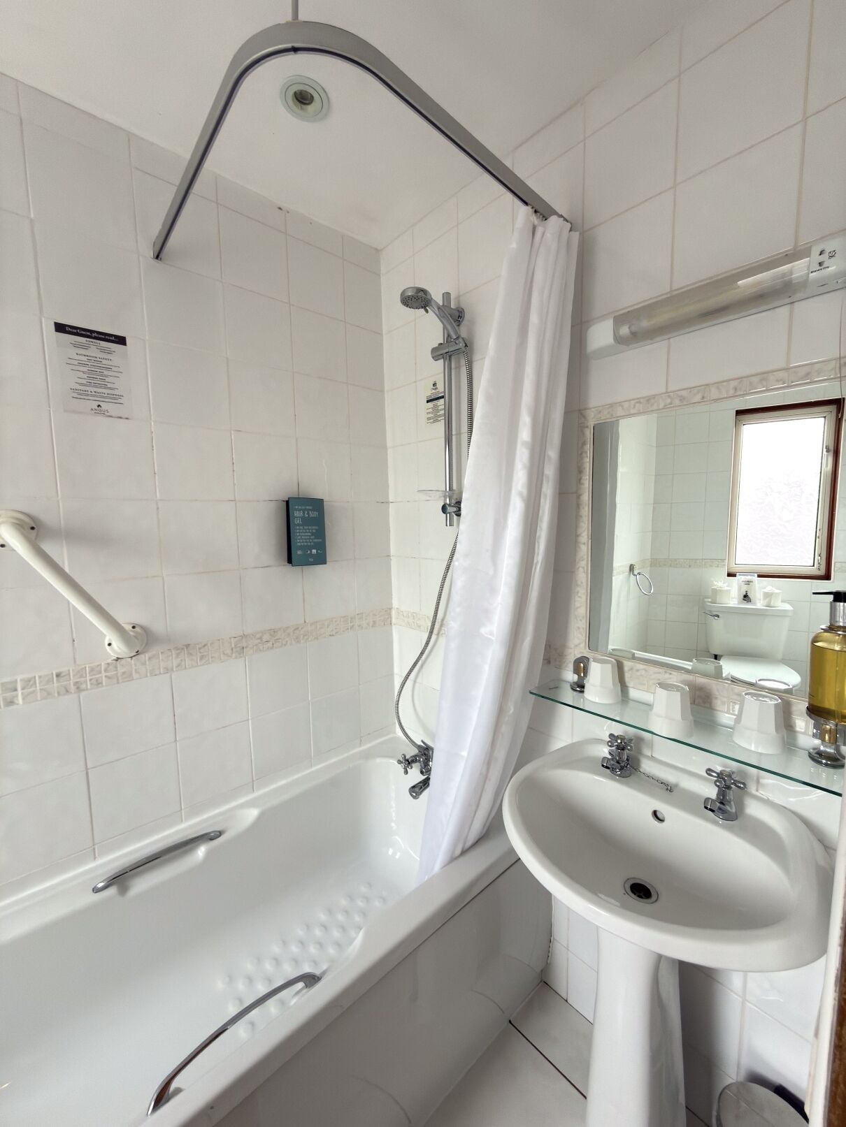 A modern bathroom with a bathtub, a shower, a glass sink, and a mirror.