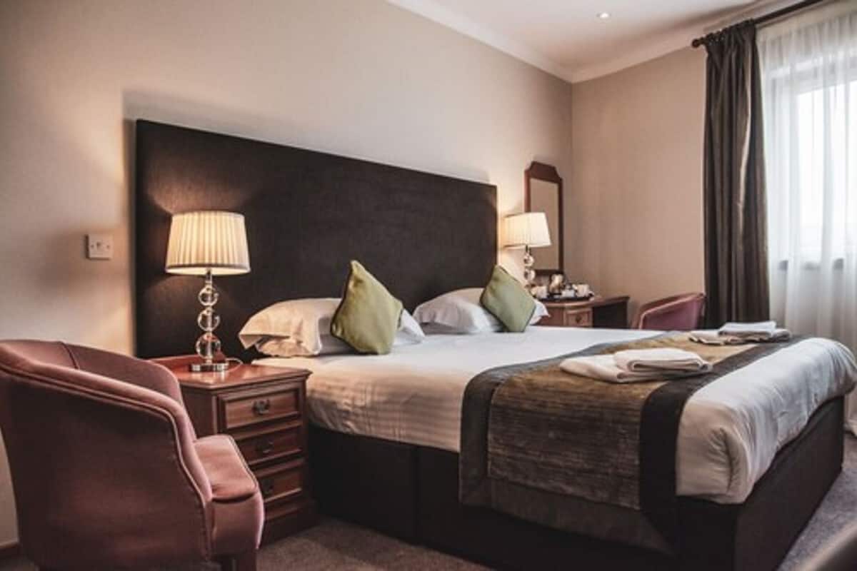 A hotel room with a large bed, two bedside tables, a chair, and a nightstand.