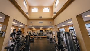 A gym with treadmills, weight machines, and a TV screen. - Emerald Greens Hotel Condo Resort (Tampa)