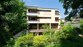 Un edificio de dos pisos con balcones y un jardín delantero, identificado con la señalización 'Central Hotel Apart'.