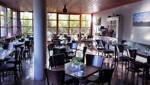 Un restaurante espacioso con varias mesas y sillas, ventanas amplias y vistas al exterior.
