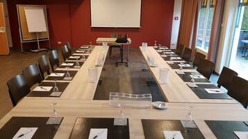 Une salle de conférence équipée d’une longue table, de chaises, d’un écran de projection et d’un tableau blanc.