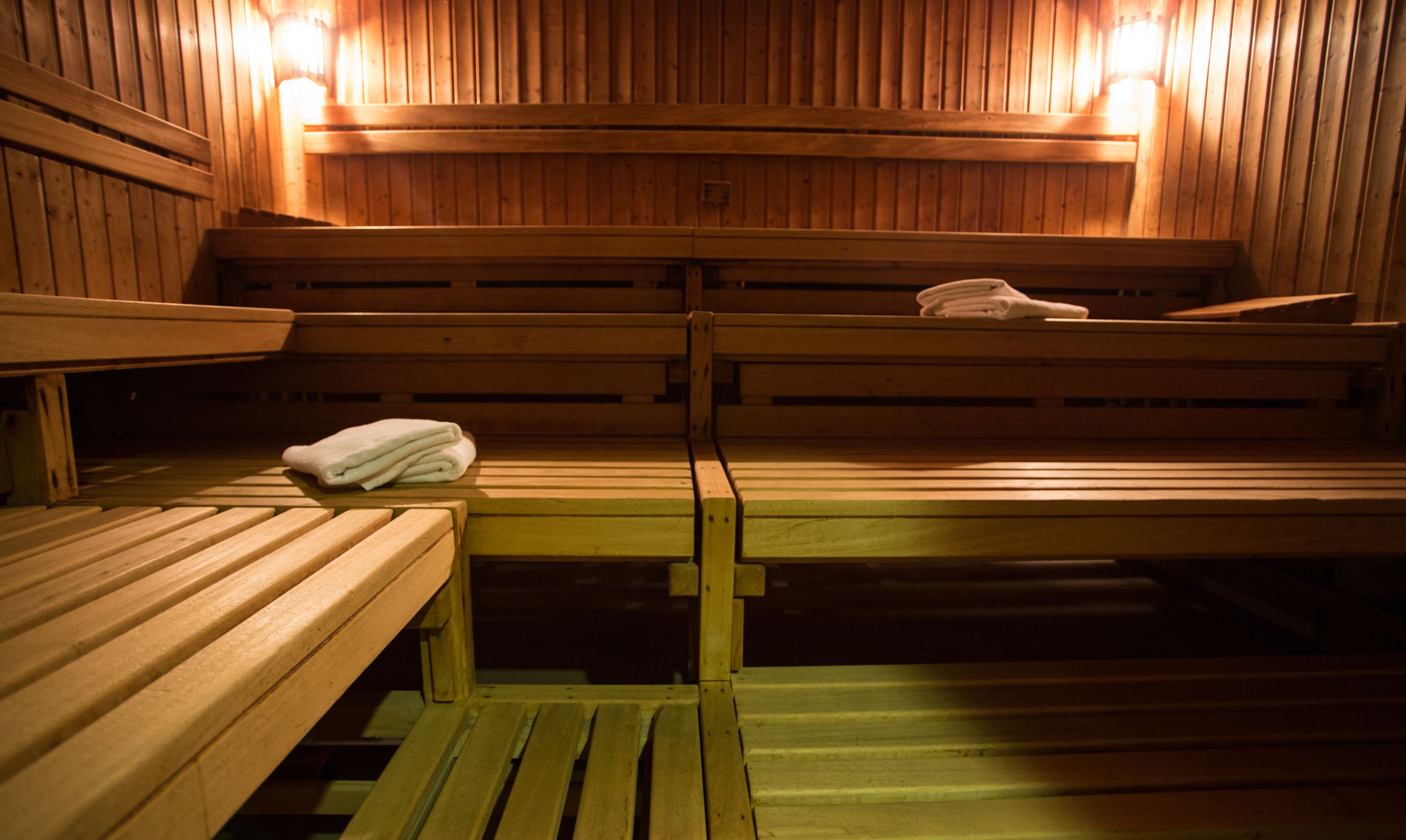 Una sauna con bancos de madera y toallas sobre uno de ellos.