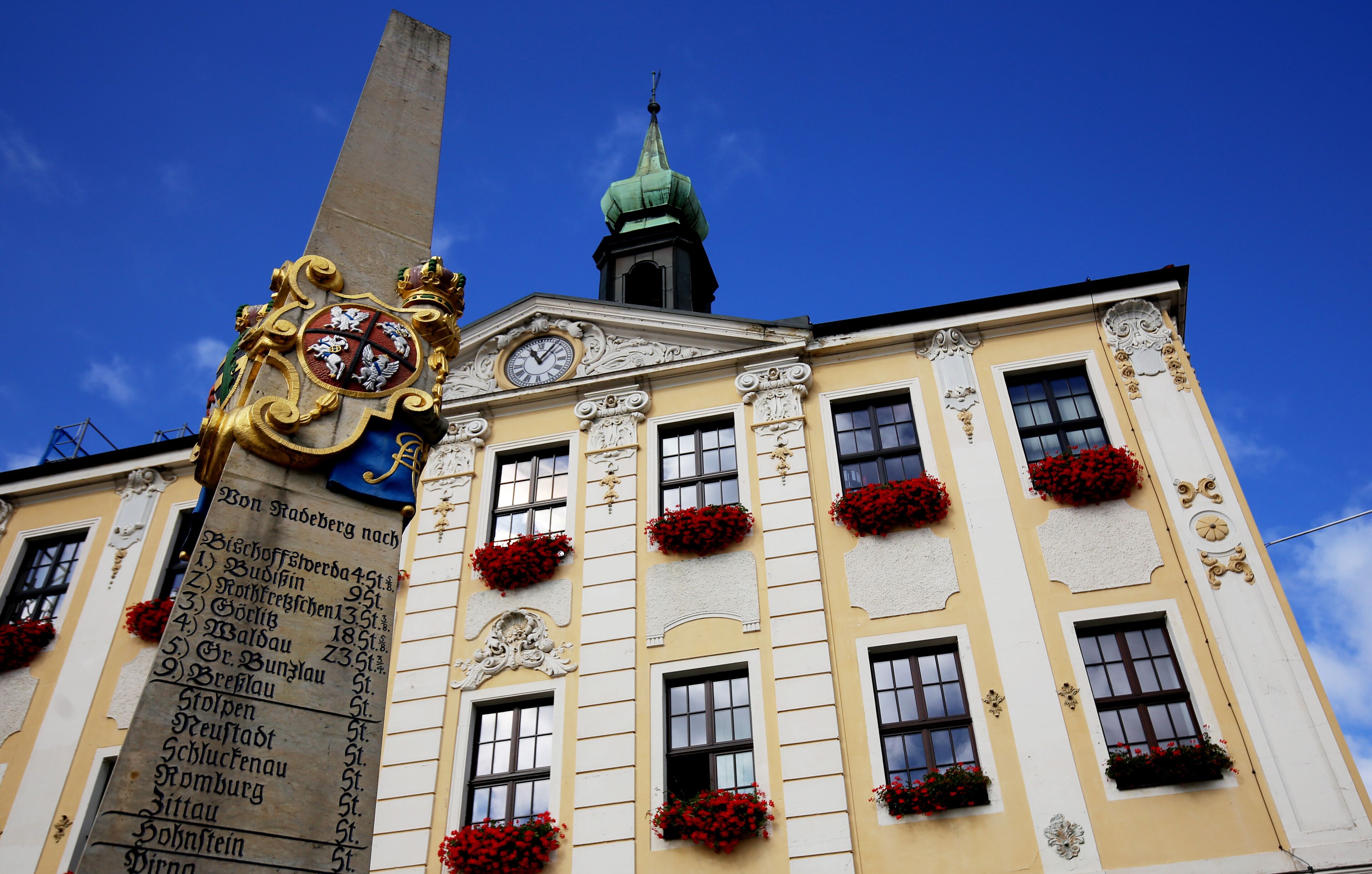 Un bâtiment historique doté d’une tour horlogée, de décorations élaborées et de jardinières aux fenêtres.