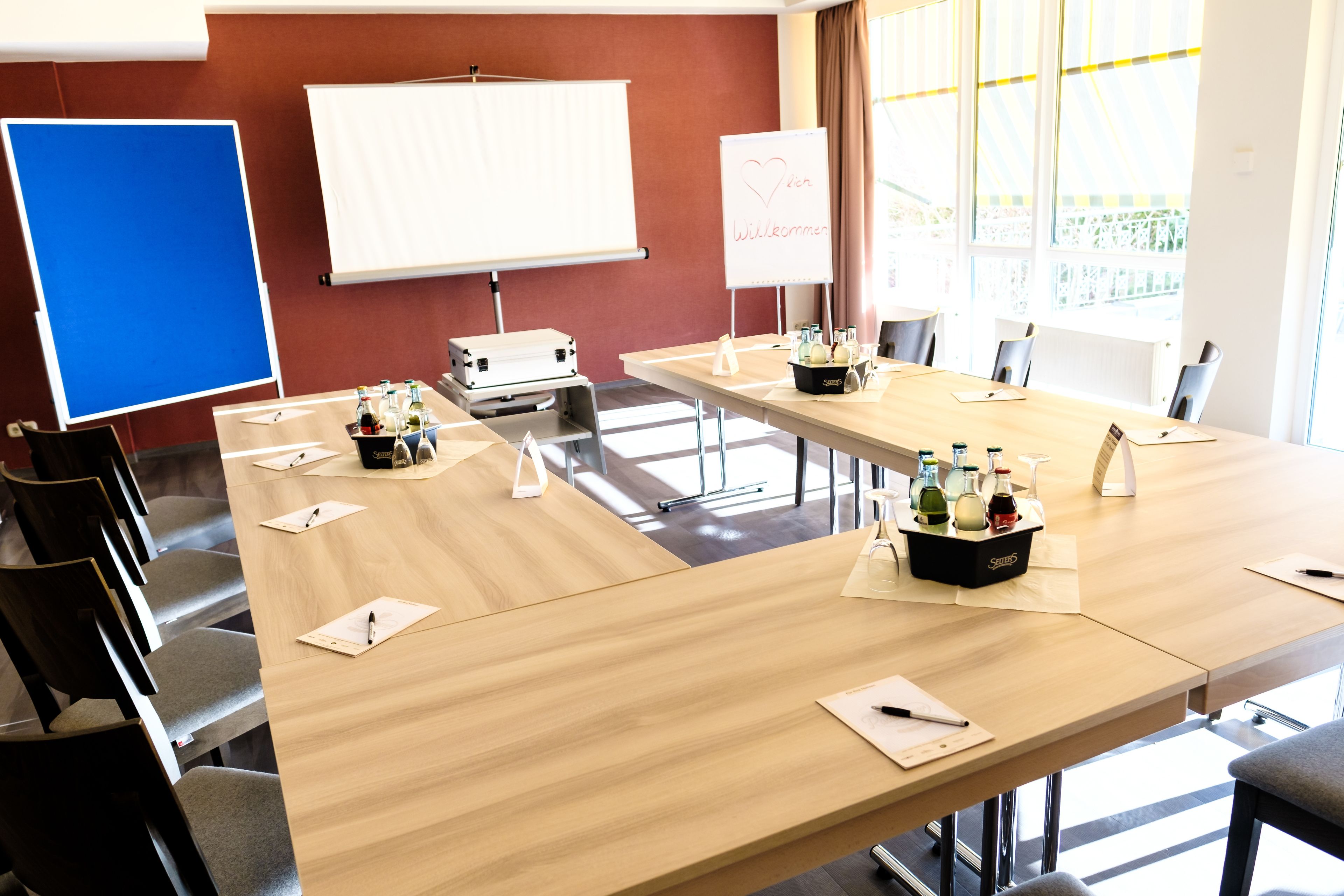 A conference room with a long table, chairs, a whiteboard, and a projector.