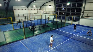 An indoor tennis court with multiple courts, a net, and players. - Hotel Sportwelt (Radeberg)