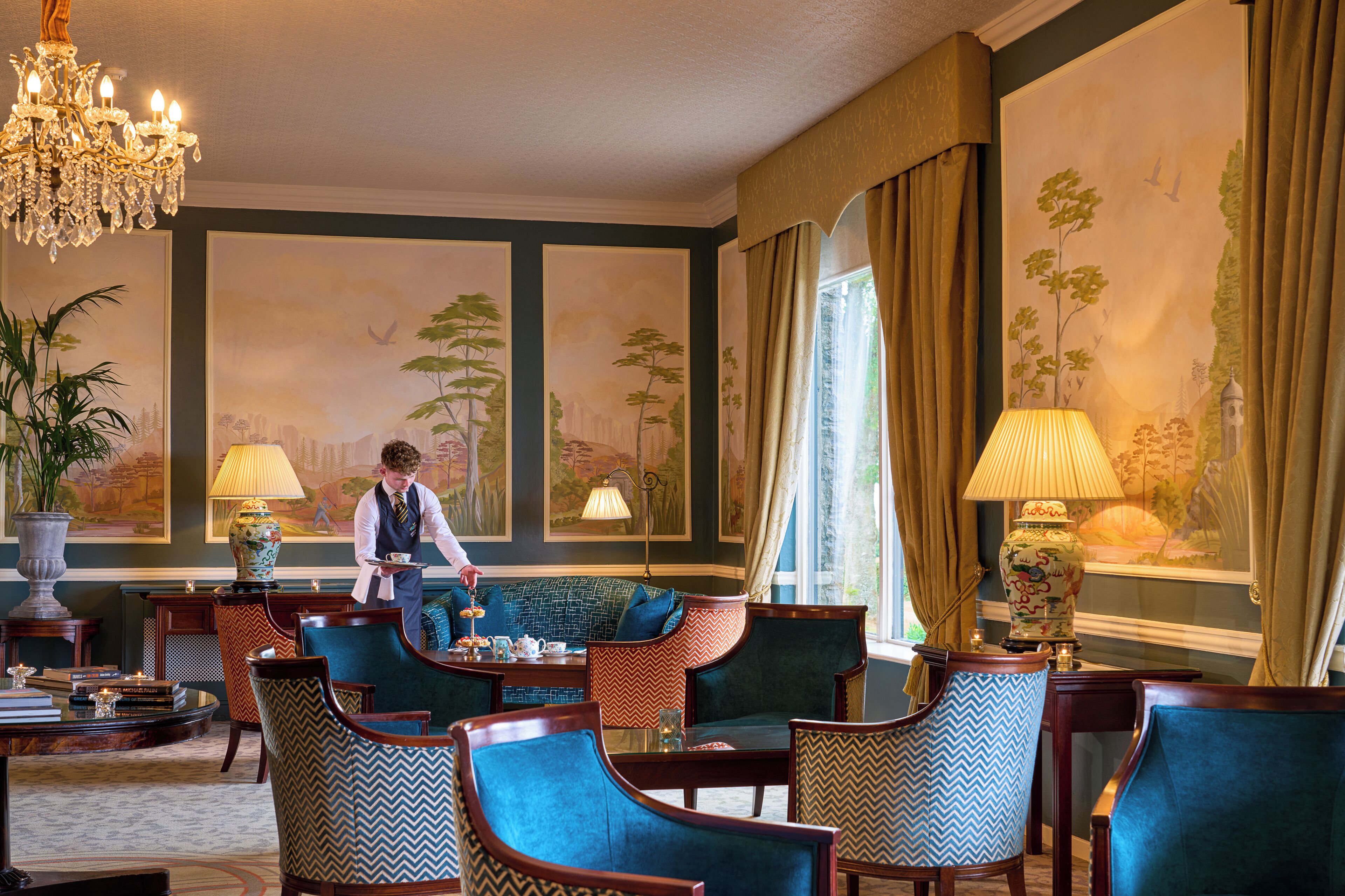 Ein formeller Speisesaal mit einem Kellner, eleganten Stühlen, einem für eine Mahlzeit gedeckten Tisch und einem großen Fenster mit Vorhängen.